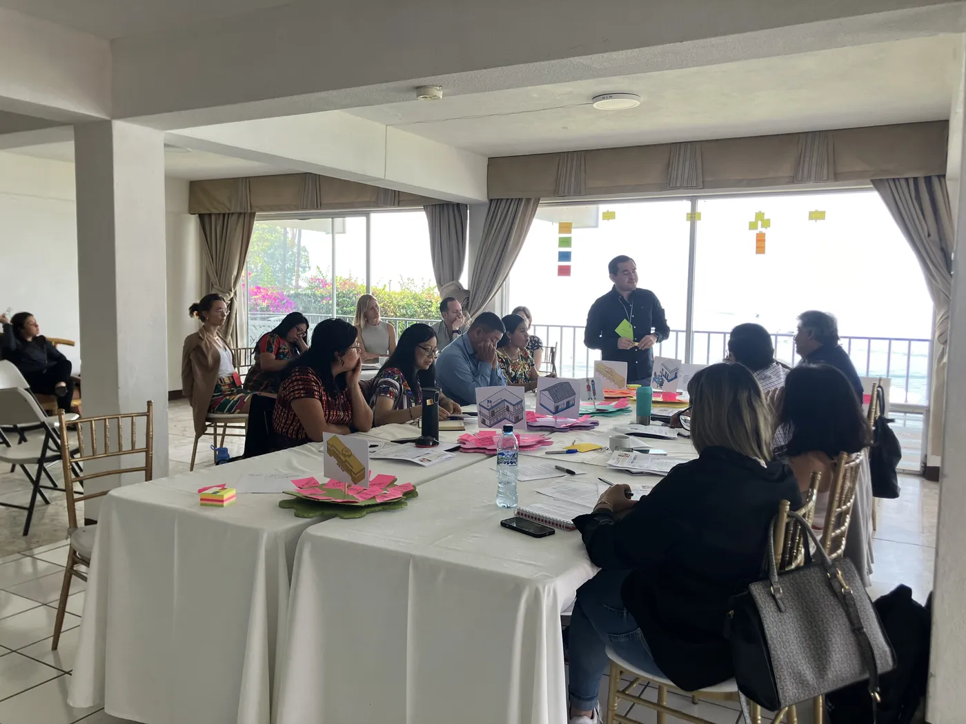 Integrantes de las organizaciones trabajan alrededor de una mesa frente a un ventanal con vista al lago.
